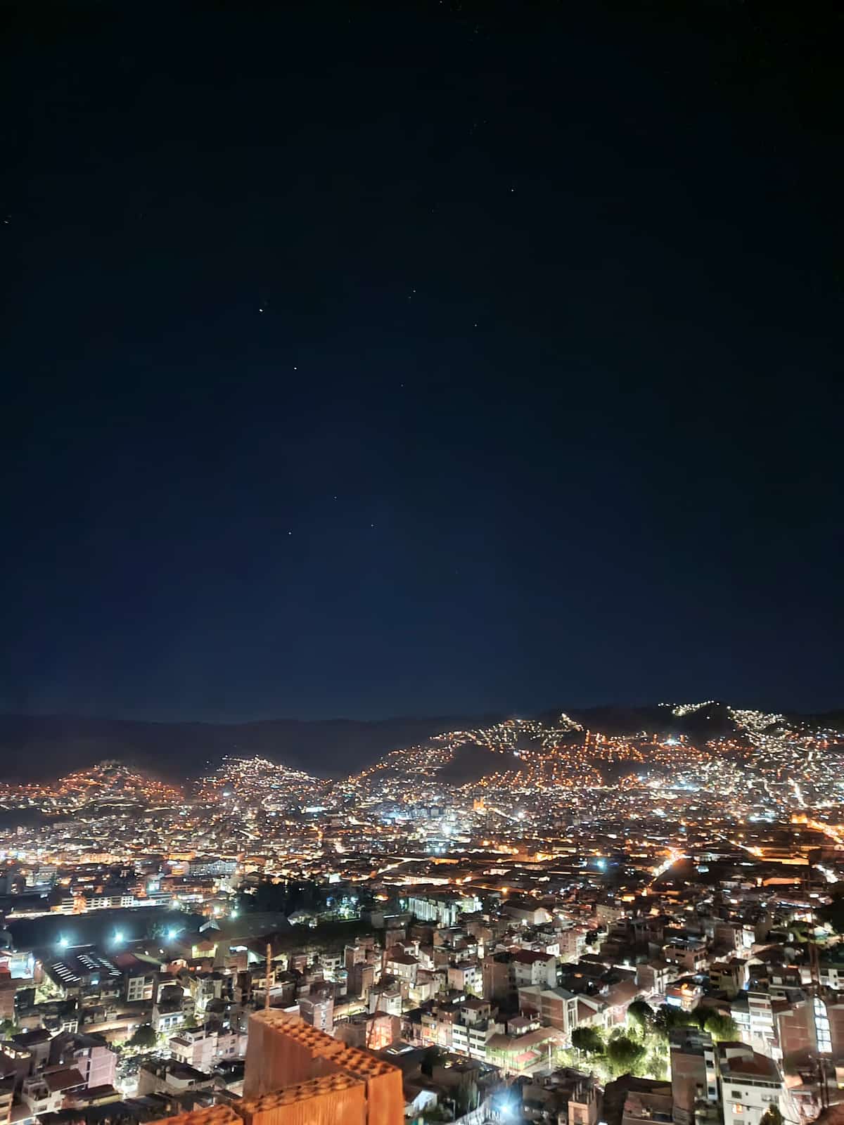 Cusco's hillside neighbourhoods lit up at night, seen from above, city lights climbing the surrounding hills.